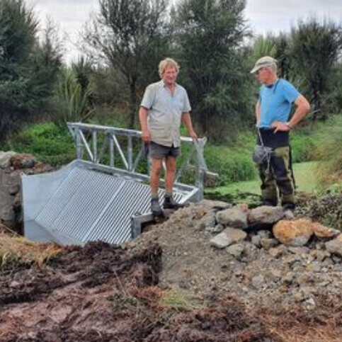 Landowner Theo Bongers (right) and consultant John Gumbley (left) inspect the newly installed koi carp barrier at the outlet of Lake Ruatuna. (Living Water)