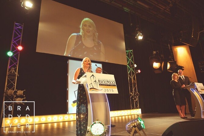 A woman speaking at a podium on stage, presenting during the Wellington Region Business Excellence Awards