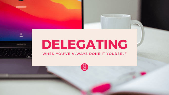 A MacBook, white cup, notebook, and pen on a desk with a pink-orange gradient screen and text, "Delegating When You've Always Done It Yourself"