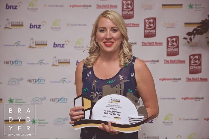 A woman smiling while holding a trophy at the Wellington Region Business Excellence Awards