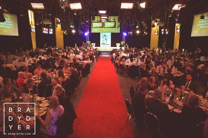 A large audience seated at tables with a red carpet leading up to a stage, set up for the Wellington Region Business Excellence Awards