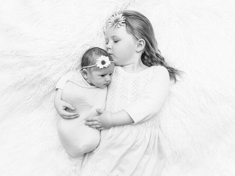 Newborn with big sister giving kisses.   Baby photography.  Papamoa Photographer.  Newborn Photographer.  Tauranga Photographer.  Newborn photoshoot.  Baby photoshoot.