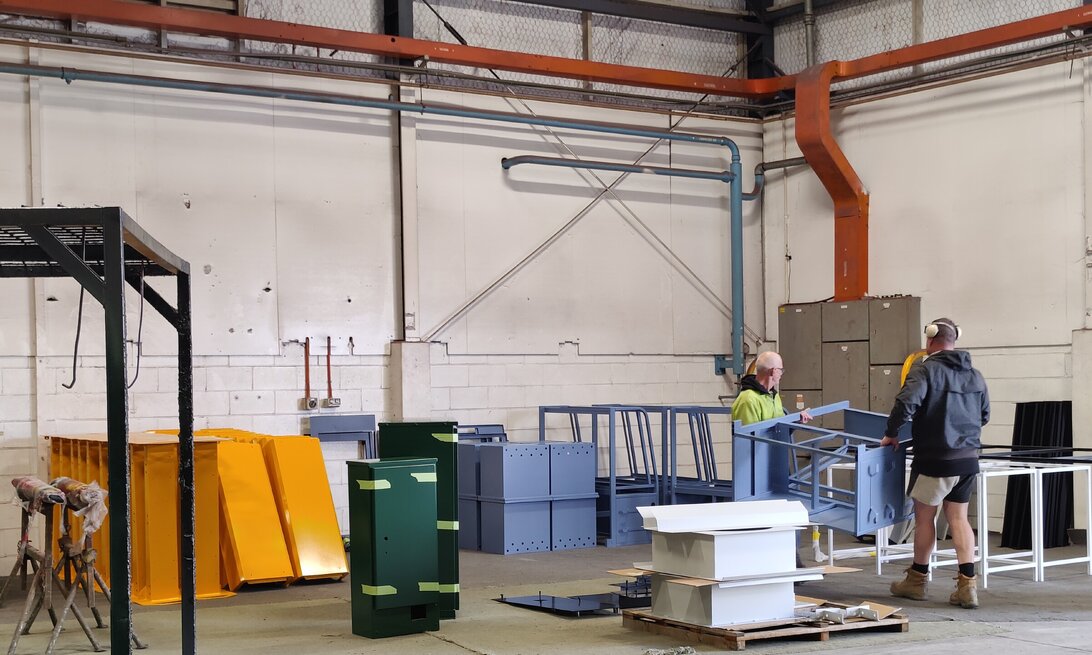 Photo of team members at HIPC carrying recently powder coated items through a warehouse