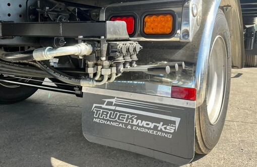 Photo of Fuso Canter salvage truck rear drivers side wheel. Hydraulic lift kit and Truckworks mudflaps are visible.