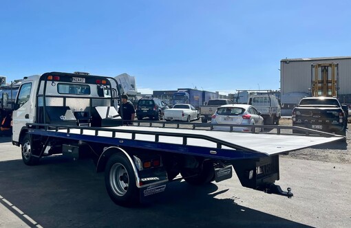 Rear passenger view of Fuso Canter salvage truck. Custom fabricated slide deck and subframe is in view, along with custom LED lighting, truckworks mud flaps, and custom tool box