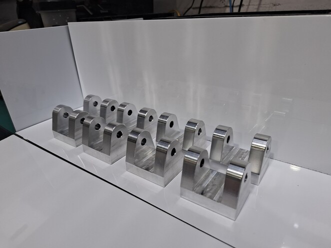 Precision-machined aluminium component with complex contours on a white cloth.