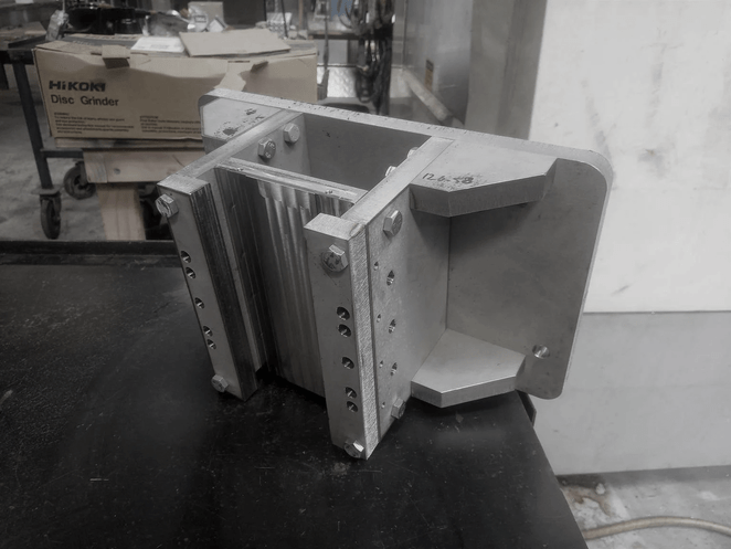 Close-up of CNC-milled aluminium block featuring recessed geometric cavities and sharp internal corners.