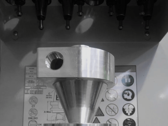 Close-up of CNC-milled aluminium block featuring recessed geometric cavities and sharp internal corners.