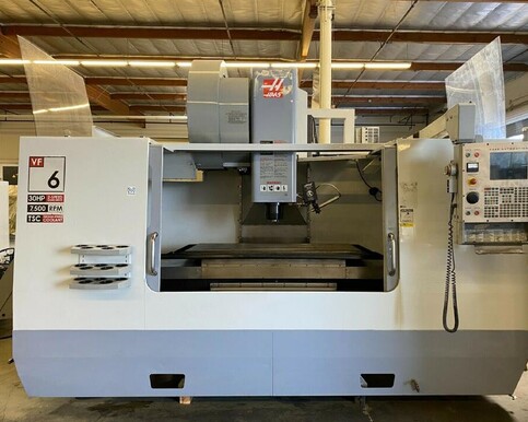 Haas VF6/50 CNC machining centre inside a workshop with high roof and lighting.