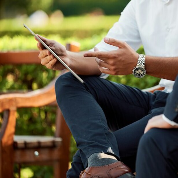 A person sitting with a client showing them information on a tablet.