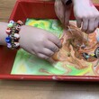 Photo of childs hands swirling paint around in a tray with toothpicks