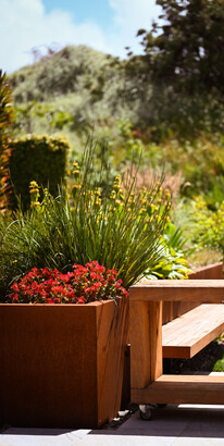 Beautifully planted corten raised planter with built-in seating and moveable outdoor counters