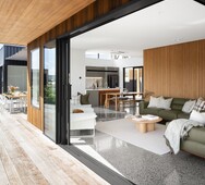 Coastal‑style living room with timber accents and polished concrete floor &mdash; Kōtare Grove