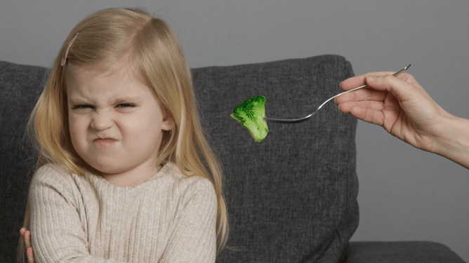 Girl screws up her nose at broccoli