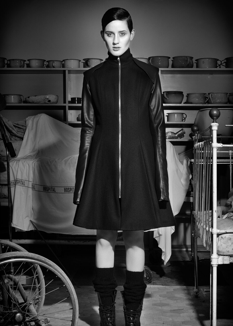 A model wearing a black zip up coat designed by Jane Sutherland. Photographed at Demolition World in Southland.