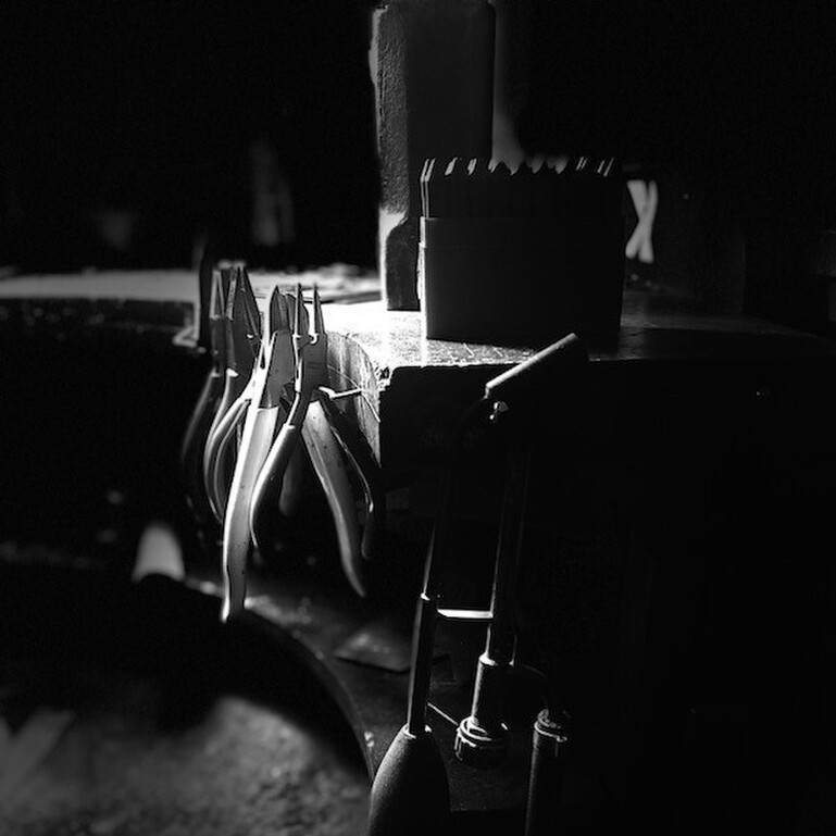 A black and white image of Jane Sutherland's work bench featuring her jewellery tools.