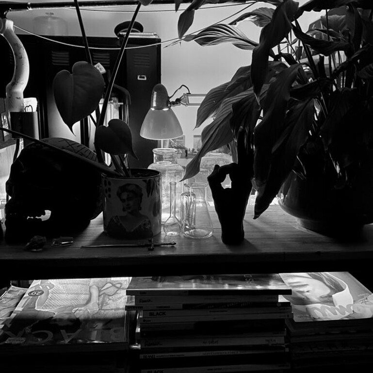 A black and white image from Jane's studio of a desk covered in ornaments and inspiration.