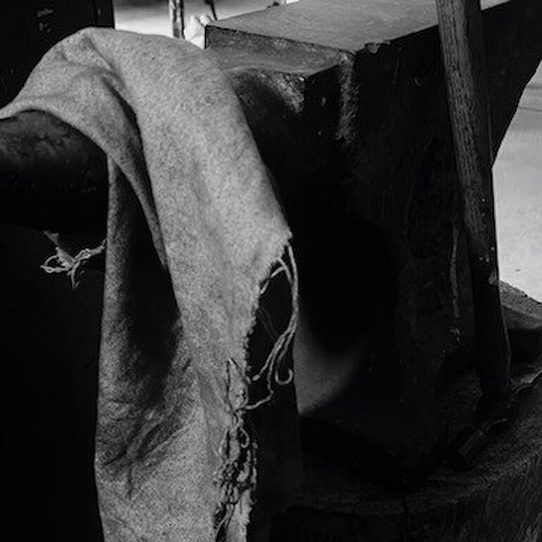 A black and white image of fabric draped over an anvil.