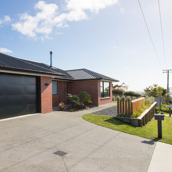 Red Brick home with timber fence and concrete driveway.