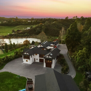 Arial view of large family home surrounded by New Zealand native bush and a beautiful sunset. 