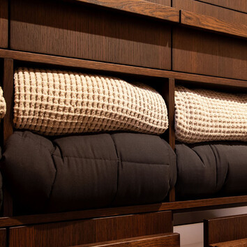 Blankets neatly folded in dark timber shelving