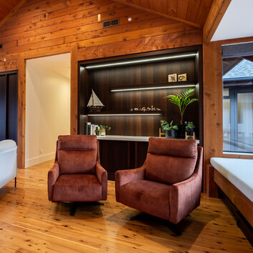 two arm chairs in a home with timber floor and walls