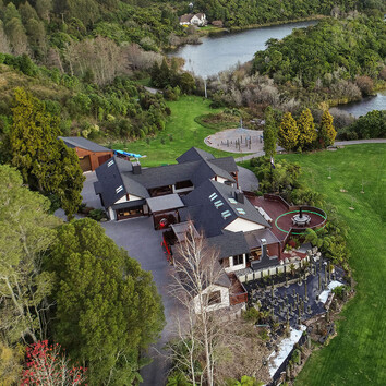 Arial view of large family home surrounded by New Zealand native bush, situated near a lake