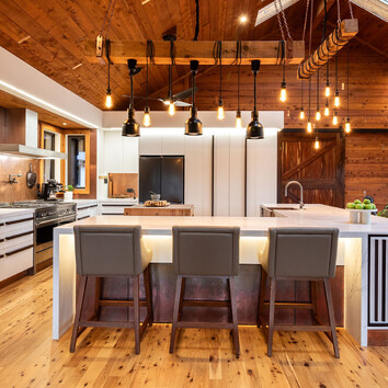 Modern kitchen with handing lights and timber floor and ceiling.