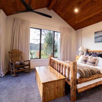 Master bedroom with rustic timber bed frame and timber rocking chair. 