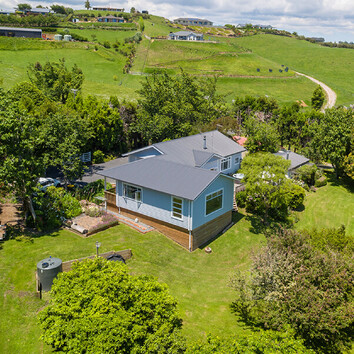 traditional light blue weatherboard home in a rural New Zealand setting. 