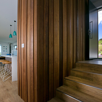 Internal timber cladding and black front door and stairs.