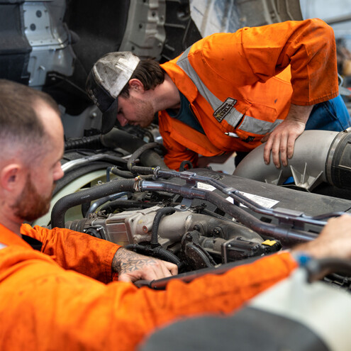 two men servicing a heavy truck engine