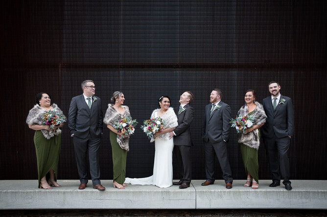 Photograph of bride and groom with bridal party stanfing in a row laught in wellingtons civic square
