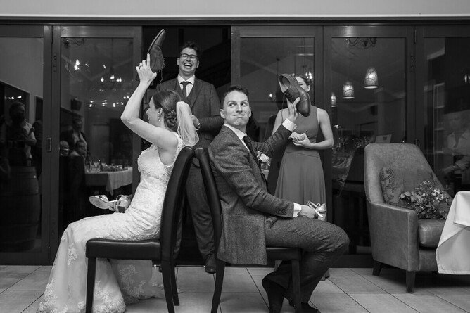 black and white photograph of bride and groom on their wedding day playing the shoe game