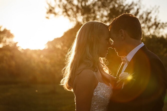 bride and groom with their head togeather in golden sunset light on their wedding day
