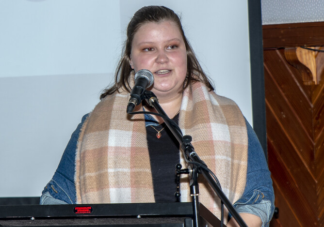 Brylee stands in front of microphone giving a speech