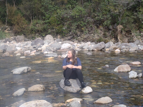 Brylee sits on rock in river