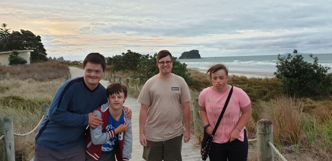 Four young people pose by beach