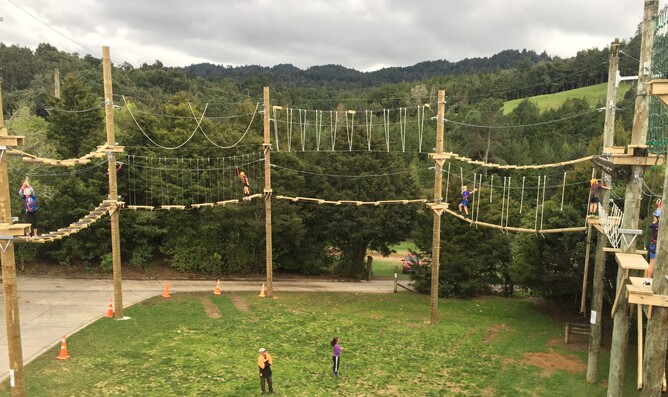 Children climb through outdoor ropes course