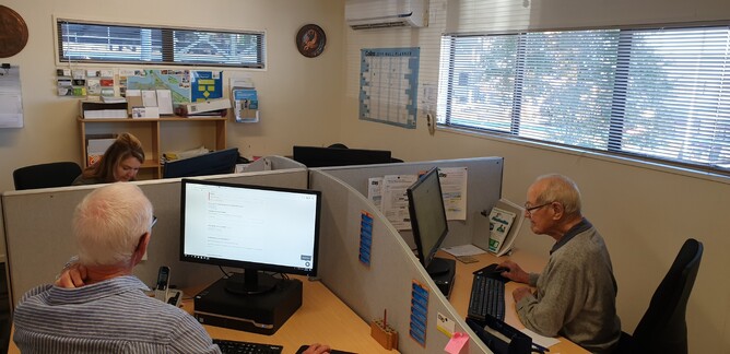 Three Citizens Advice Bureau volunteers sit at computers
