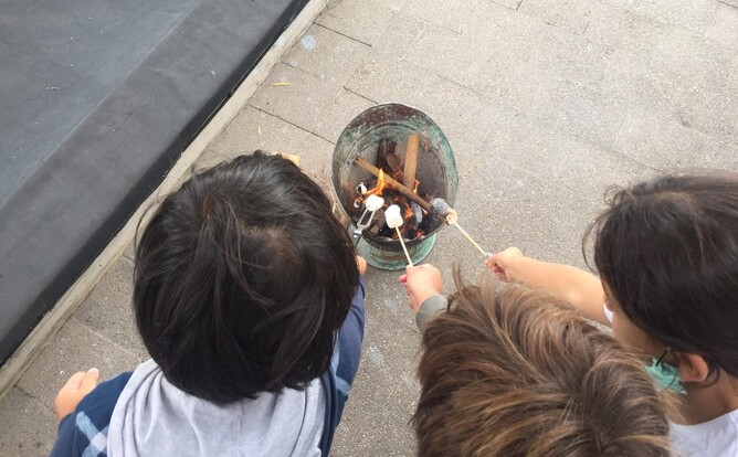 Three children hold marshmallows over fire