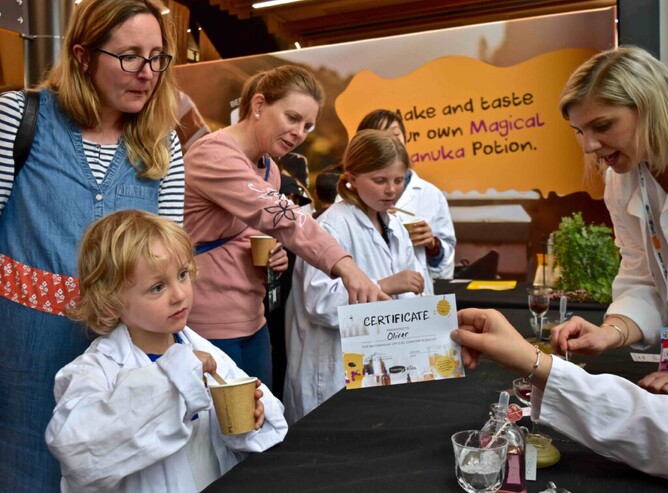 Children in lab coats make manuka honey potion as part of STEMFest