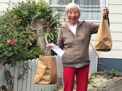 Recipient of grocery shopping assistance holds bags of food