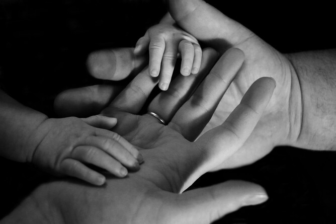 Two adult and two children's hands pose on top of each other