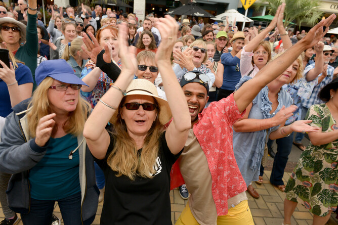 Audience members clap and wave hands outside