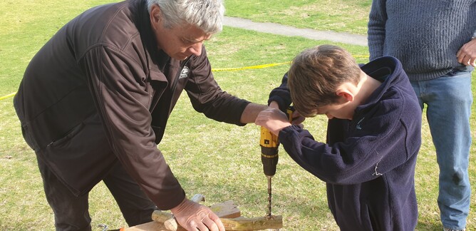 Stu Thompson from ICONZ assists boy from Welcome Bay Primary using drill