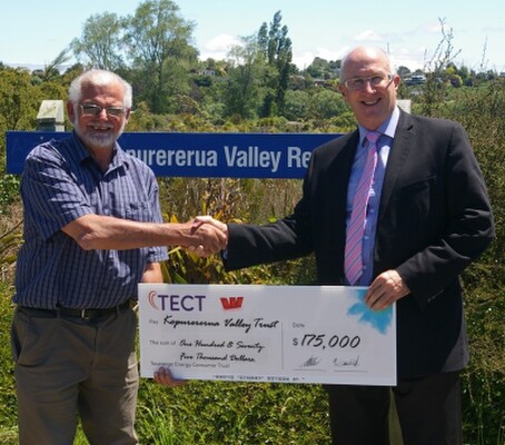 Bill Holland shakes hand of Kopurererua Valley Rotary Centennial Trust representative with large $175,000 cheque