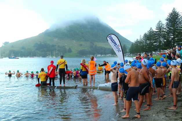 Young people in and out of water by Mount Maunganui