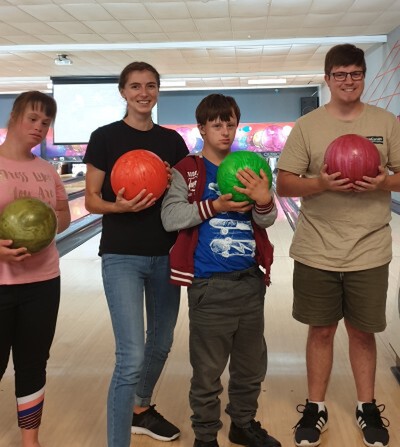 Three young people and facilitator pose with bowling balls in hand