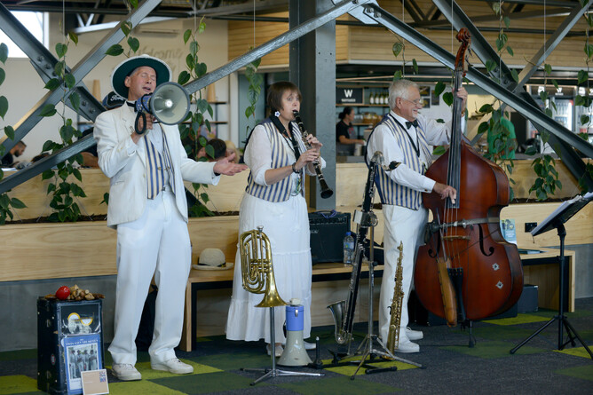 Three musicians in white pinstripe costumers play music